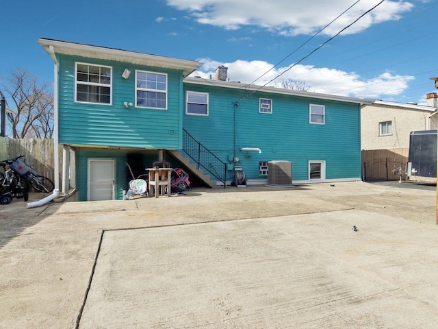 rear view of house featuring central AC unit, fence, and driveway