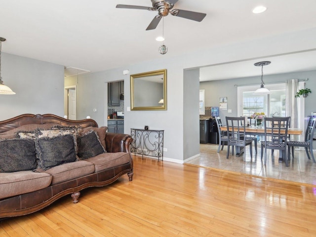 living area with a ceiling fan, recessed lighting, light wood-style floors, and baseboards