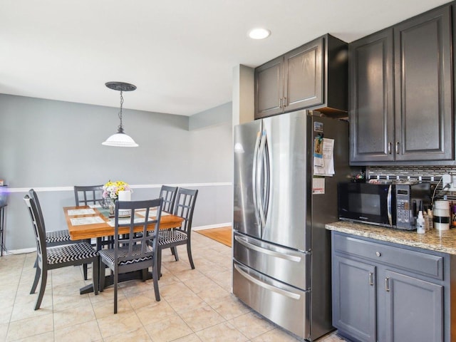 kitchen with baseboards, freestanding refrigerator, hanging light fixtures, black microwave, and backsplash