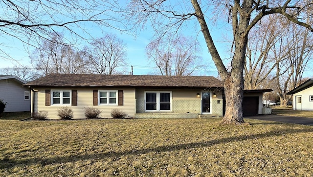 ranch-style home featuring aphalt driveway, an attached garage, brick siding, and a front yard