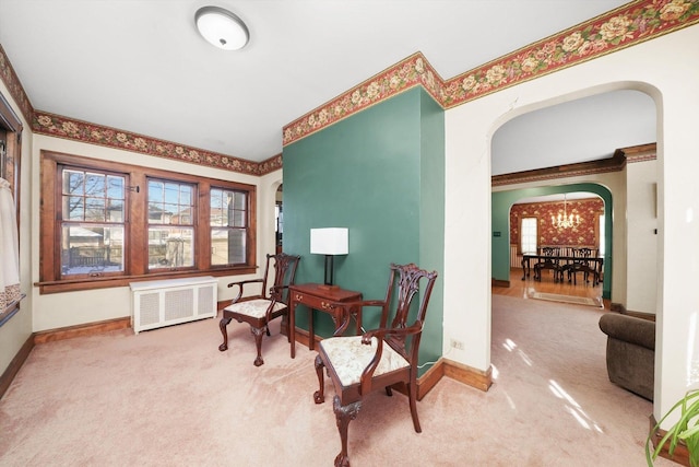 living area featuring radiator, carpet, arched walkways, and a wealth of natural light