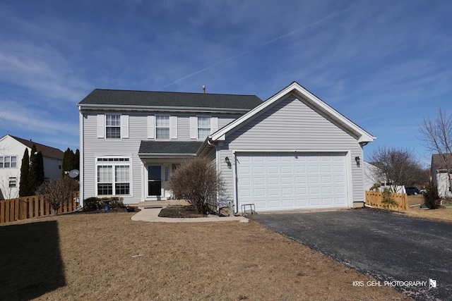 traditional-style home featuring an attached garage, fence, driveway, and roof with shingles