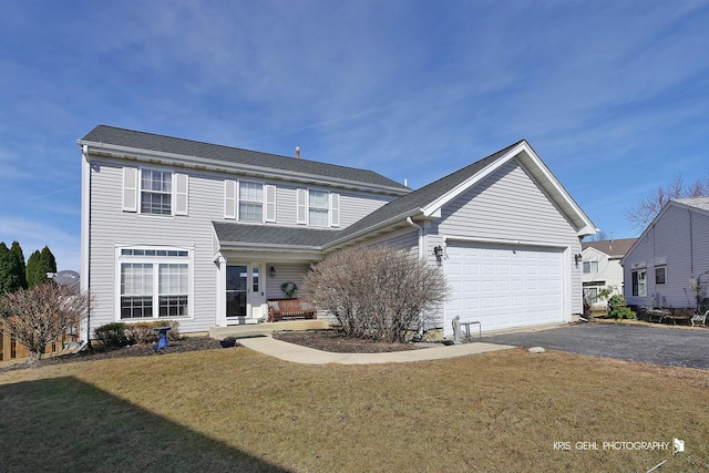 traditional-style home featuring aphalt driveway, a front yard, an attached garage, and a shingled roof