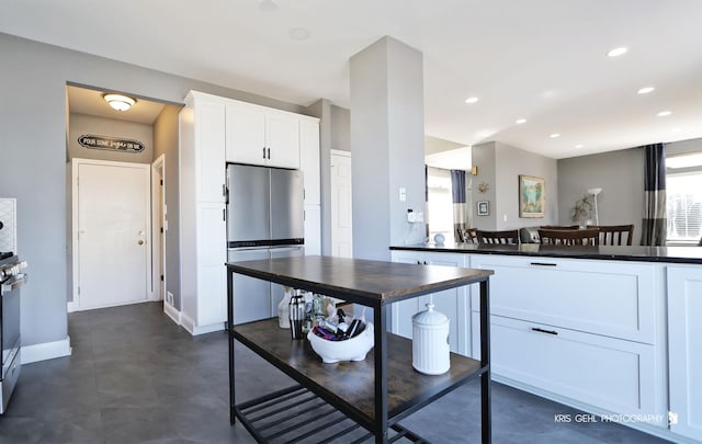 kitchen with dark countertops, white cabinetry, recessed lighting, stainless steel appliances, and baseboards