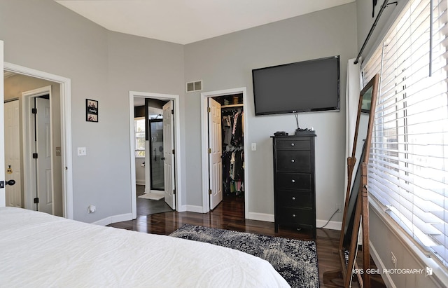 bedroom featuring visible vents, a walk in closet, dark wood finished floors, a closet, and baseboards