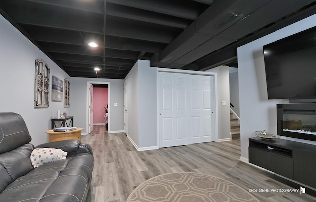 living room with visible vents, baseboards, wood finished floors, and stairs