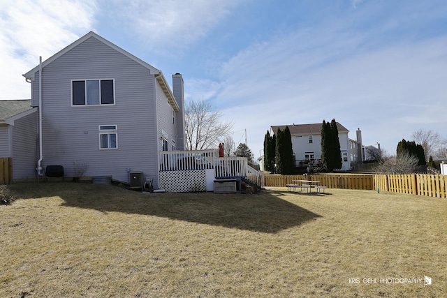 rear view of property with cooling unit, a lawn, fence, and a wooden deck