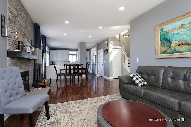 living room with dark wood-style floors, baseboards, recessed lighting, a fireplace, and stairs