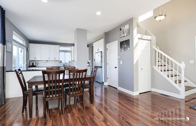 dining room featuring dark wood finished floors, plenty of natural light, stairway, and visible vents