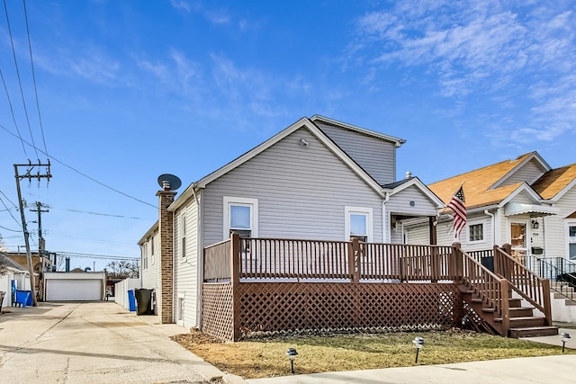 rear view of property featuring a detached garage, an outbuilding, and a deck