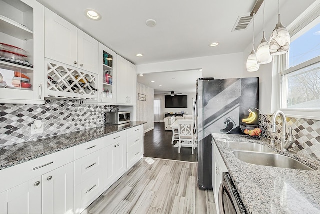 kitchen featuring a sink, stainless steel appliances, light wood-type flooring, and white cabinets