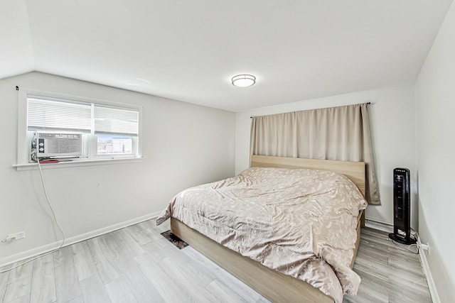 bedroom with vaulted ceiling, cooling unit, baseboards, and wood finished floors