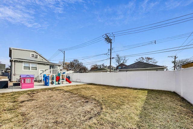 view of yard featuring a patio area, a playground, and a fenced backyard