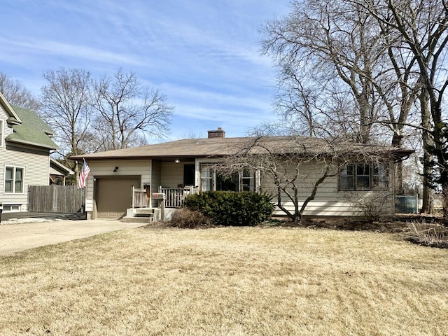 back of property featuring fence, driveway, an attached garage, a yard, and a chimney