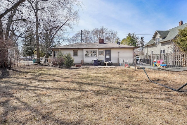 rear view of property with a patio area, a chimney, a yard, and fence