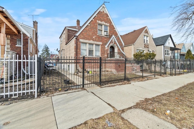 tudor home featuring a residential view, brick siding, and a fenced front yard