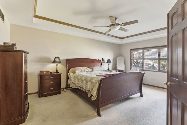 bedroom featuring a tray ceiling, baseboards, and light carpet