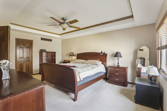 bedroom featuring visible vents, a raised ceiling, light carpet, and a ceiling fan