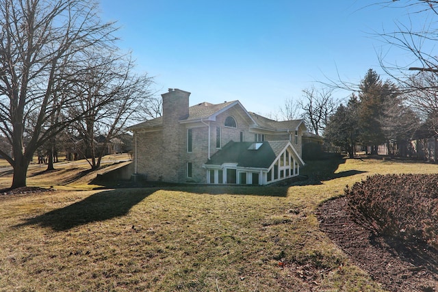 view of side of property featuring a lawn, stone siding, and a chimney