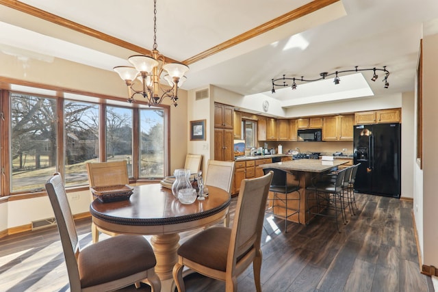 dining room with baseboards, visible vents, dark wood finished floors, a tray ceiling, and an inviting chandelier