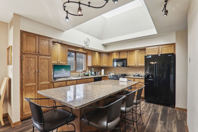 kitchen with dark wood finished floors, a kitchen island, brown cabinets, and black appliances