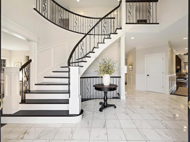 stairs featuring a decorative wall, marble finish floor, and ornamental molding