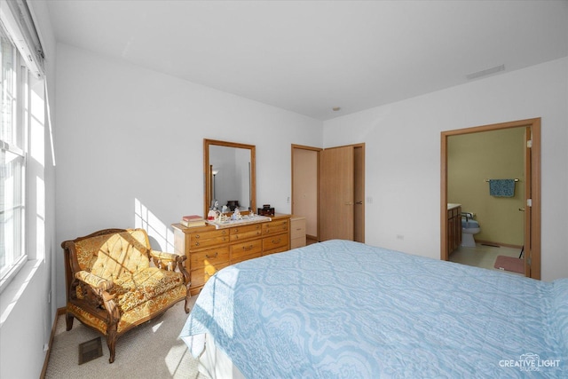 bedroom with ensuite bath, visible vents, and light carpet