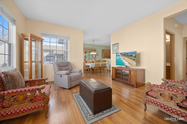 living area with plenty of natural light, light wood-style floors, and an inviting chandelier