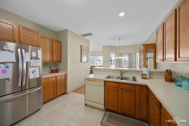 kitchen with visible vents, a sink, freestanding refrigerator, a peninsula, and dishwasher