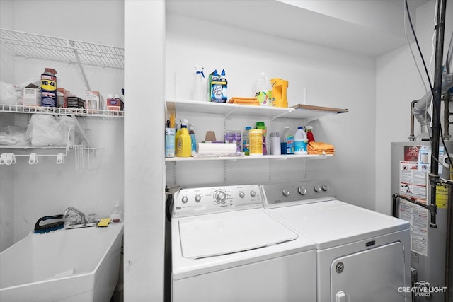 clothes washing area featuring separate washer and dryer, laundry area, gas water heater, and a sink