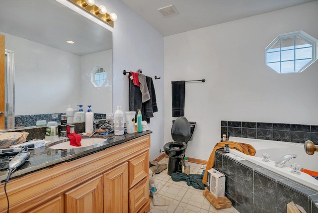 bathroom featuring a bath, visible vents, vanity, and baseboards