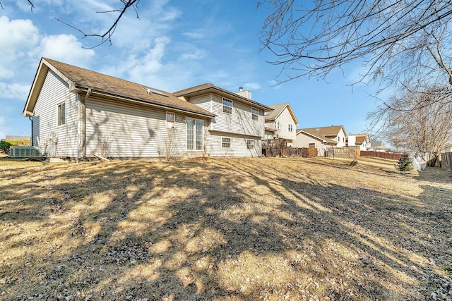 rear view of property with a chimney and fence