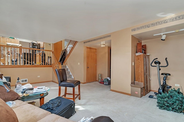 carpeted living area with stairway and baseboards