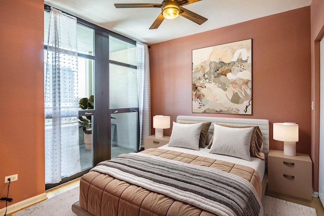 bedroom featuring a ceiling fan, baseboards, and expansive windows