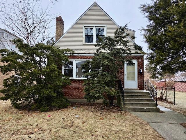 bungalow-style home featuring brick siding, a chimney, and fence