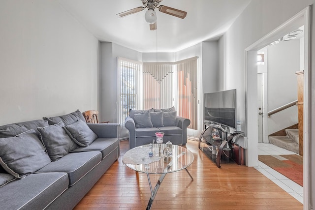 living area featuring stairway, a ceiling fan, and light wood finished floors