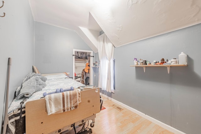 bedroom featuring visible vents, baseboards, a walk in closet, and light wood-style flooring