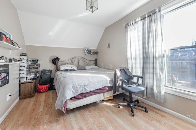 bedroom with light wood-style flooring, baseboards, and lofted ceiling