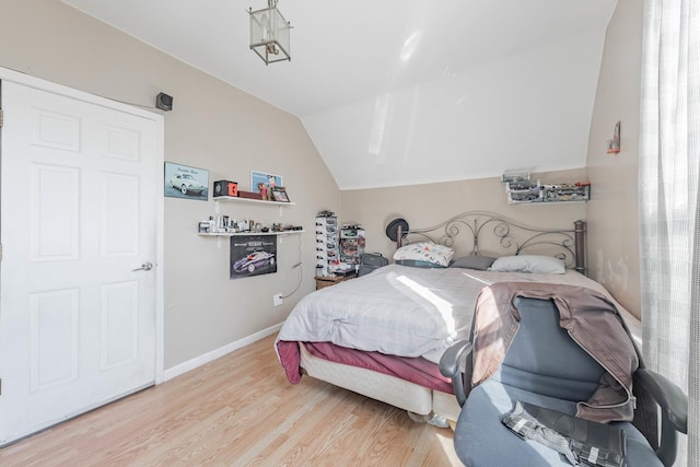 bedroom featuring light wood-type flooring, baseboards, and vaulted ceiling