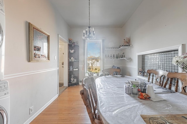 dining room with an inviting chandelier, light wood-style flooring, washer / clothes dryer, and baseboards