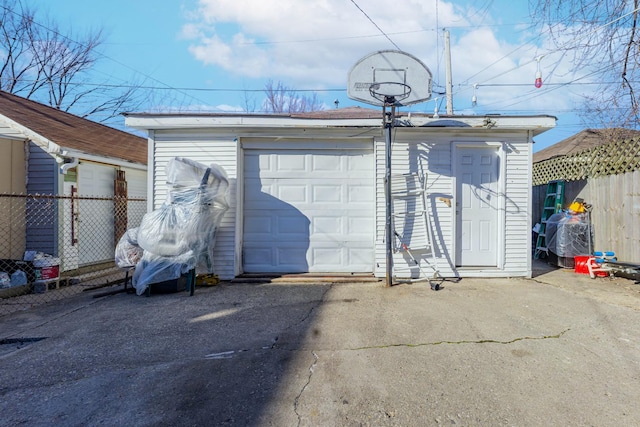 detached garage featuring driveway and fence