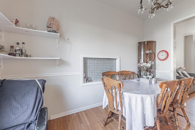 dining area featuring baseboards, wood-type flooring, and a notable chandelier