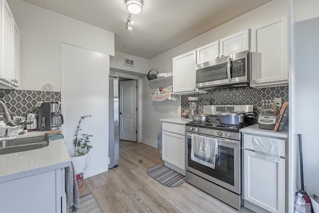 kitchen featuring light wood-type flooring, a sink, open shelves, white cabinetry, and stainless steel appliances