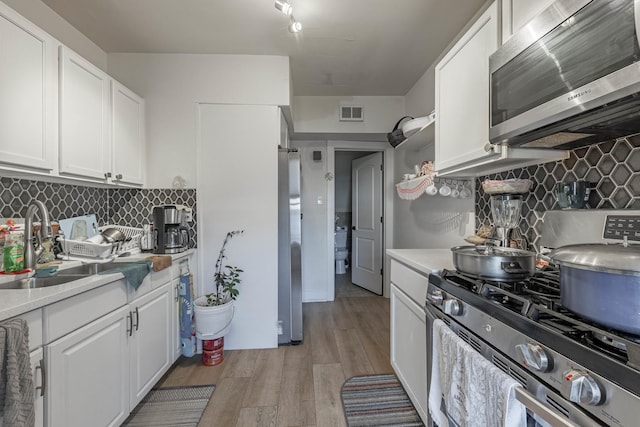 kitchen with light wood-style flooring, a sink, light countertops, white cabinets, and appliances with stainless steel finishes