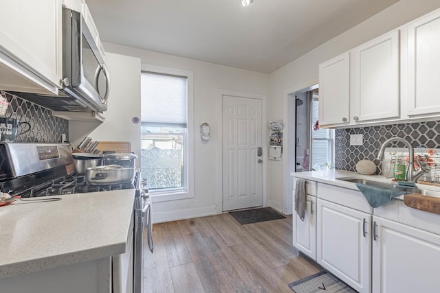 kitchen with a sink, light wood-style flooring, white cabinetry, and stainless steel appliances