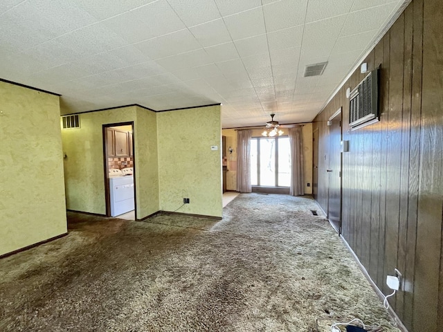 spare room with visible vents, carpet, ornamental molding, and wooden walls