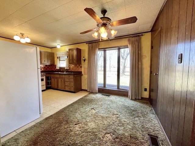 kitchen with visible vents, a sink, dark countertops, freestanding refrigerator, and wooden walls