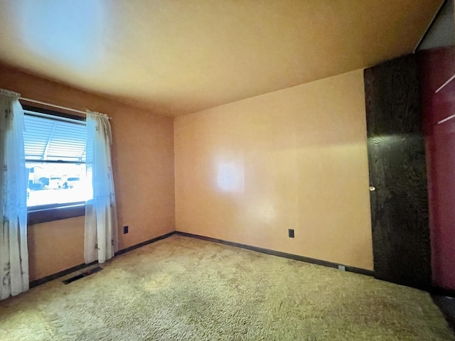 carpeted spare room with visible vents and baseboards