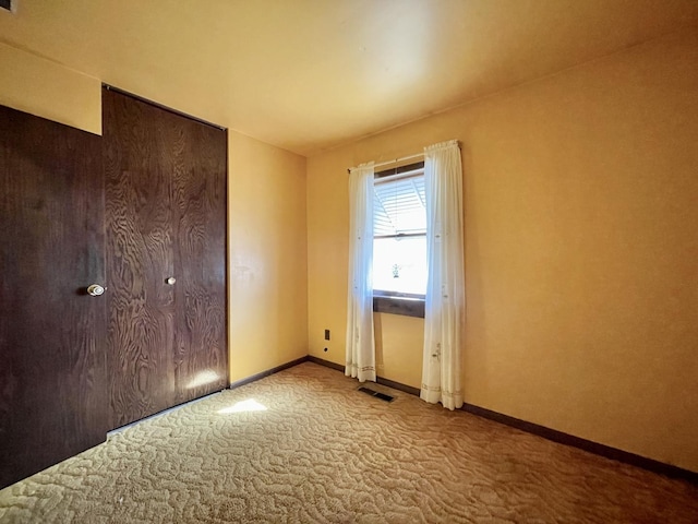 unfurnished bedroom featuring visible vents, baseboards, and carpet flooring