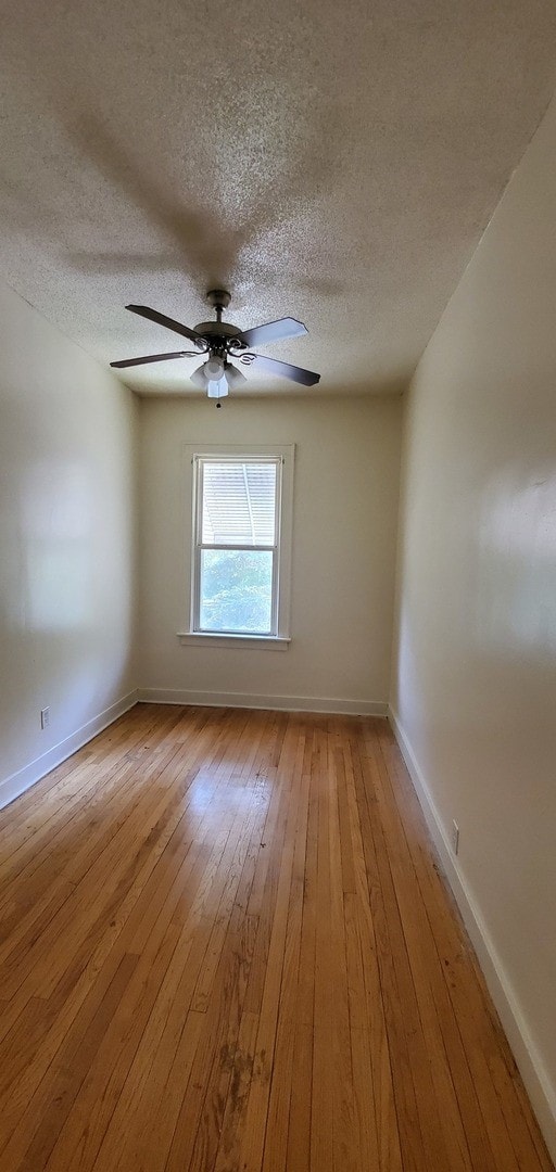 unfurnished room featuring baseboards, a textured ceiling, light wood-style flooring, and a ceiling fan